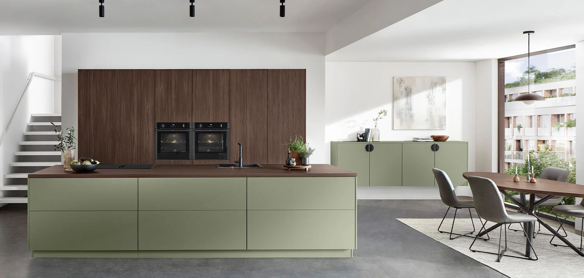 Designküche mit Insel in Grün und Hochschrankwand in dunklem Holz